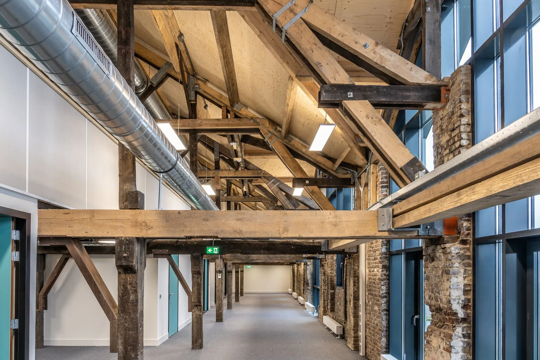 a converted warehouse corridor with exposed timber beams, brick piers and new glazing