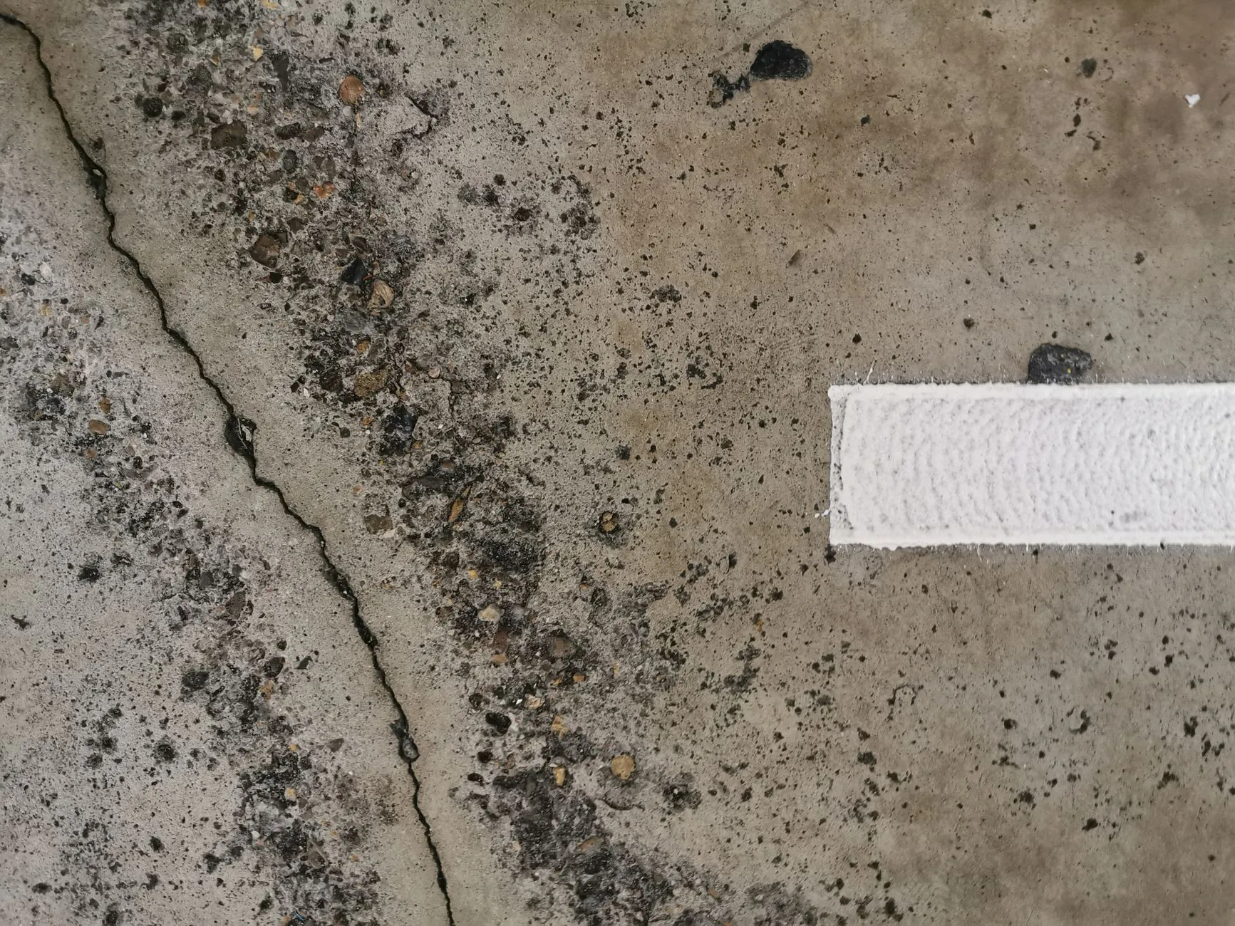 A crack in a concrete wall sealed with a filled repair band across it