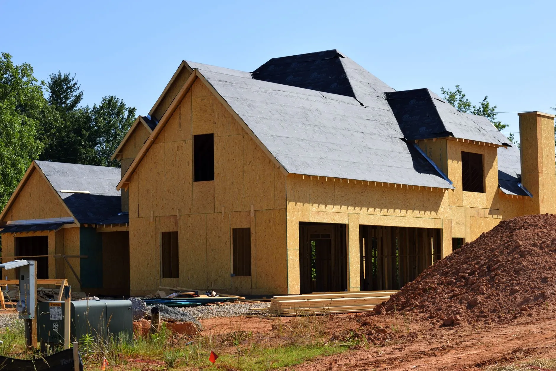 a newly sheathed house with another under construction behind it