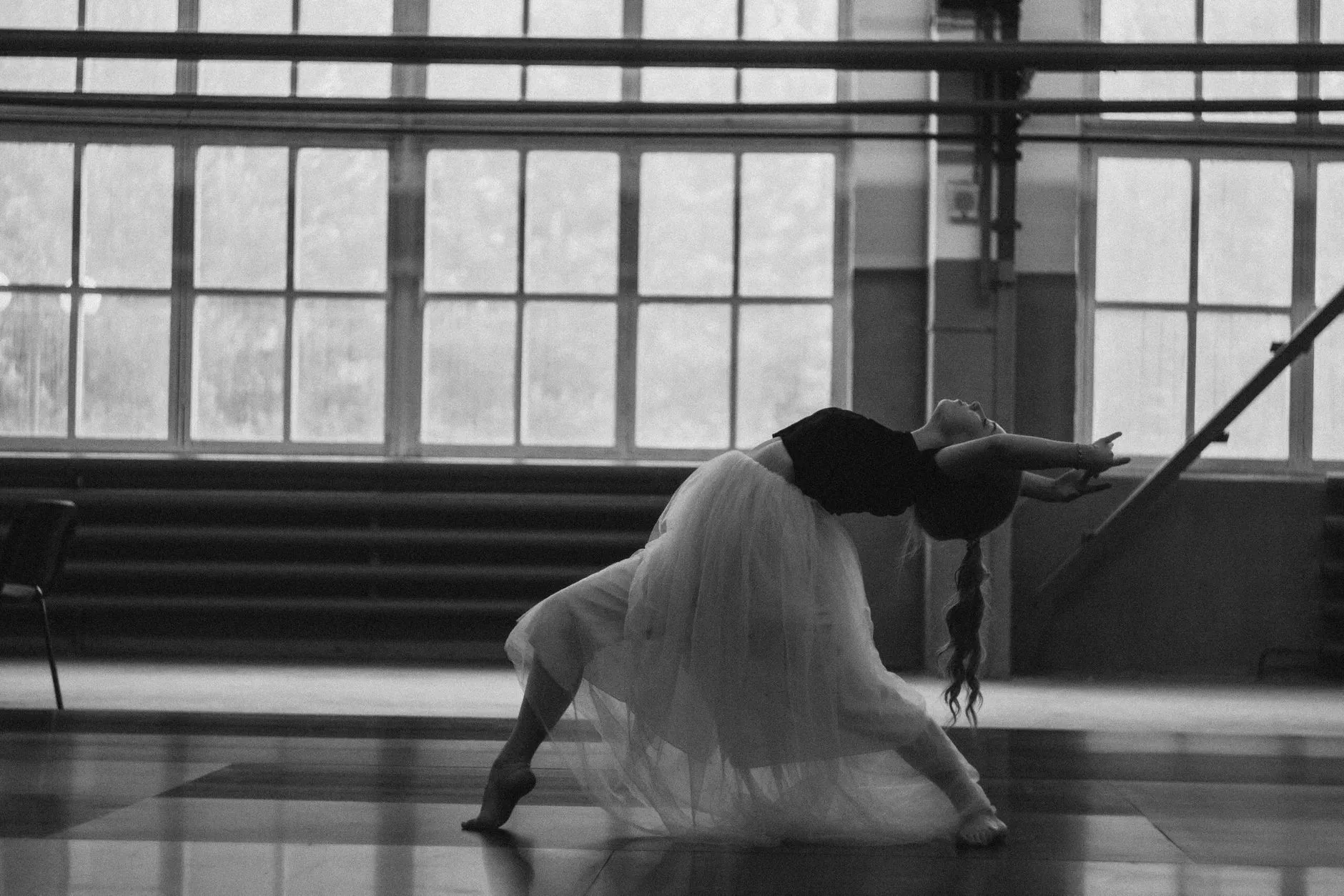 dancer in a deep backbend by tall windows, in black and white
