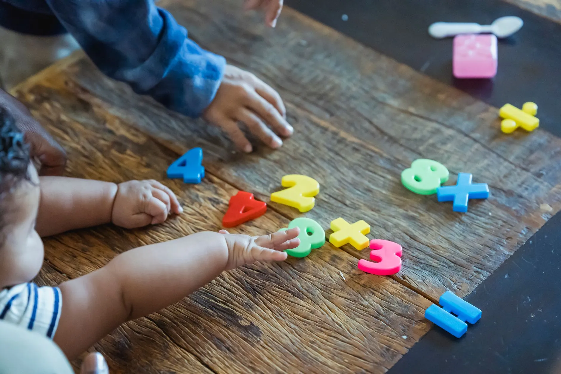 Child's hands arranging colorful number toys on a table