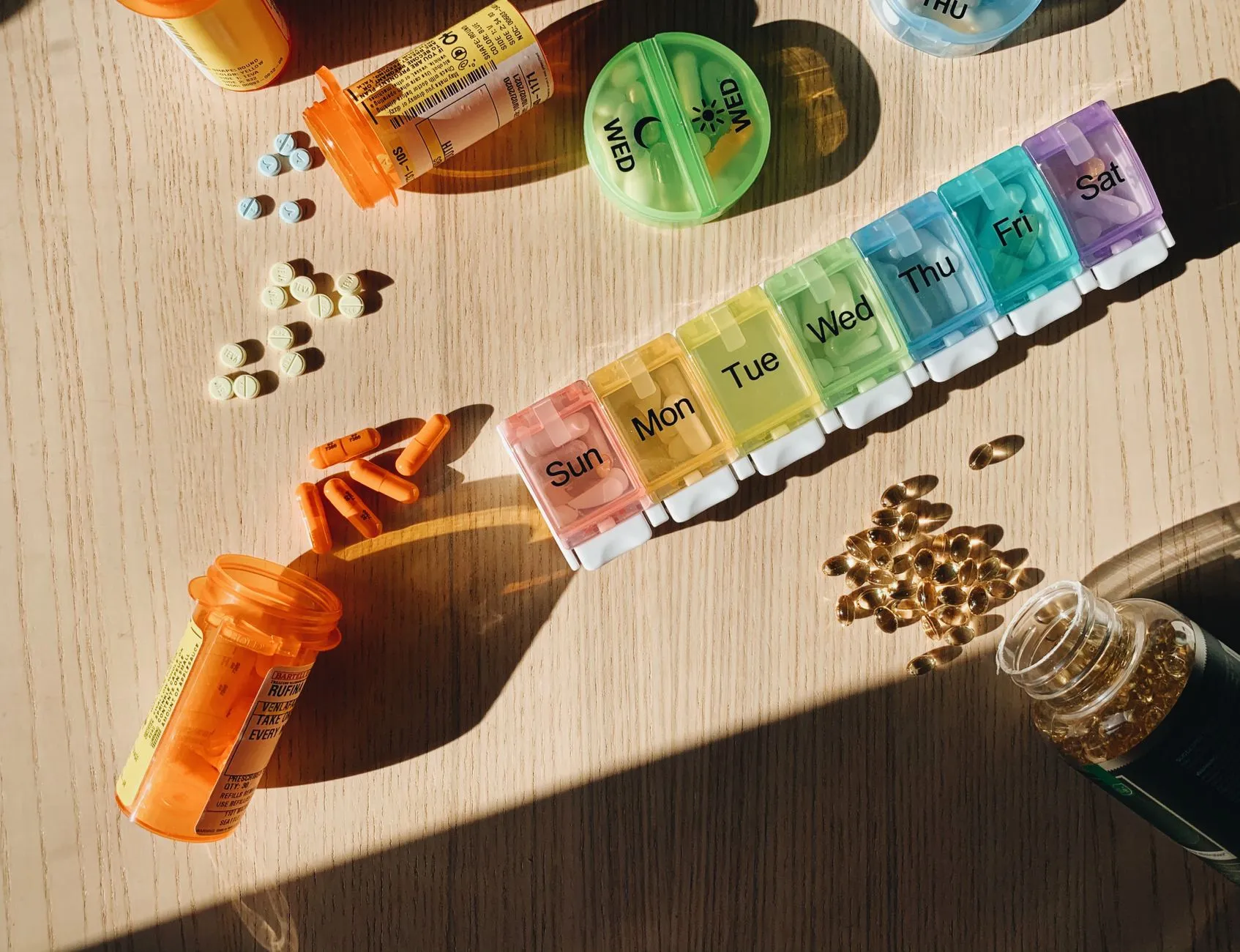 pill bottles and a weekly pill organizer on a sunlit table