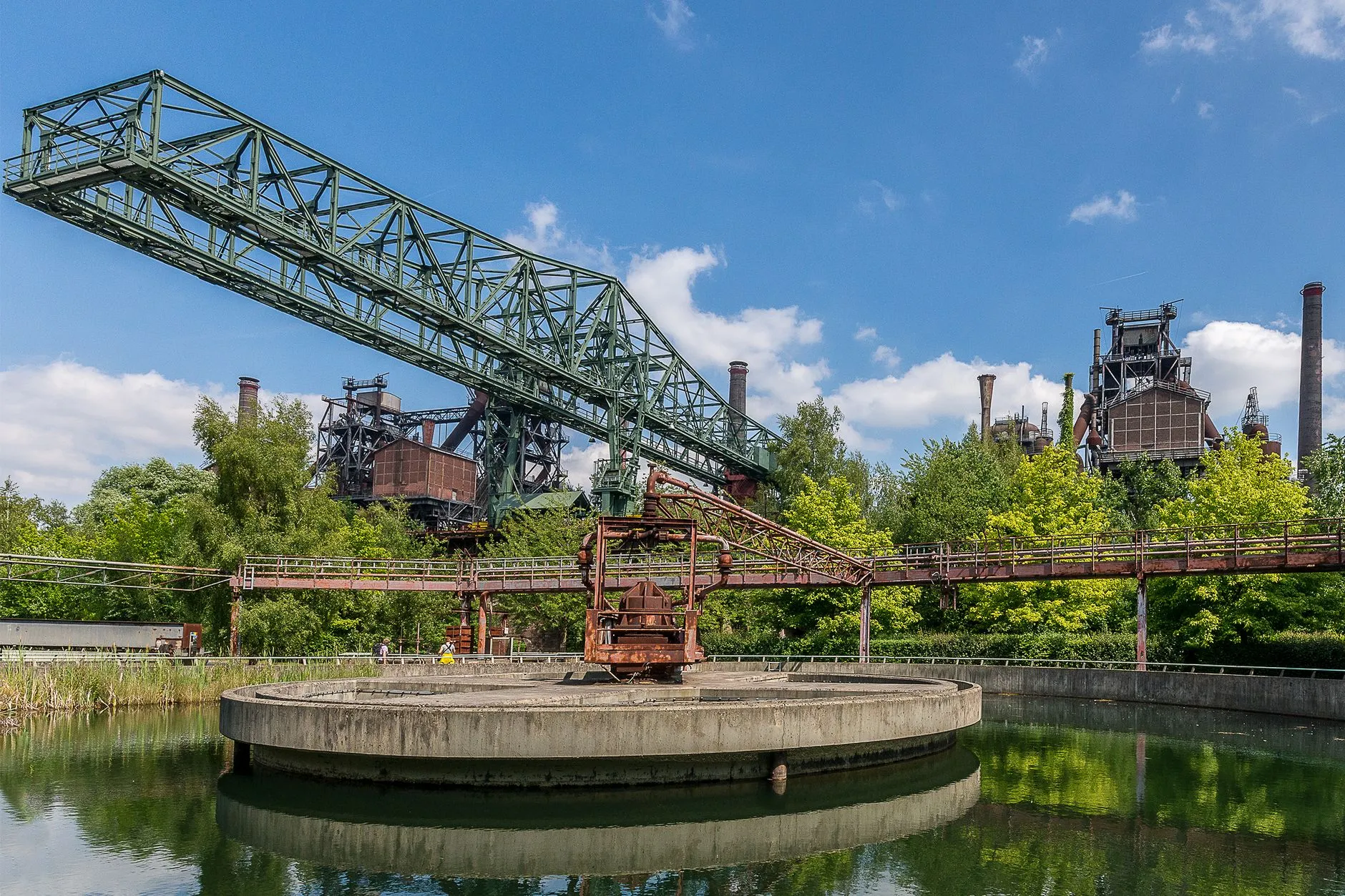an old industrial gantry over water being reclaimed by greenery