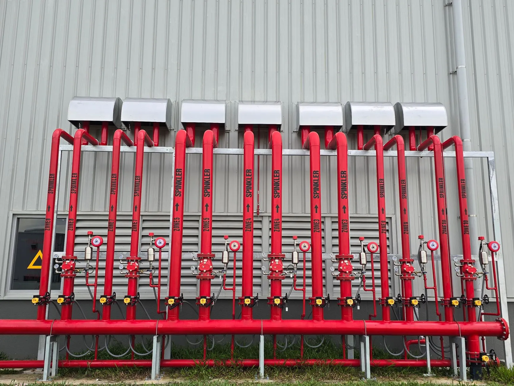 a row of fire sprinkler pipes under a ceiling