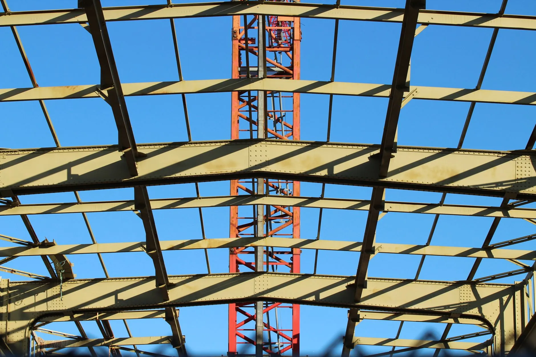 a yellow steel roof frame against a blue sky
