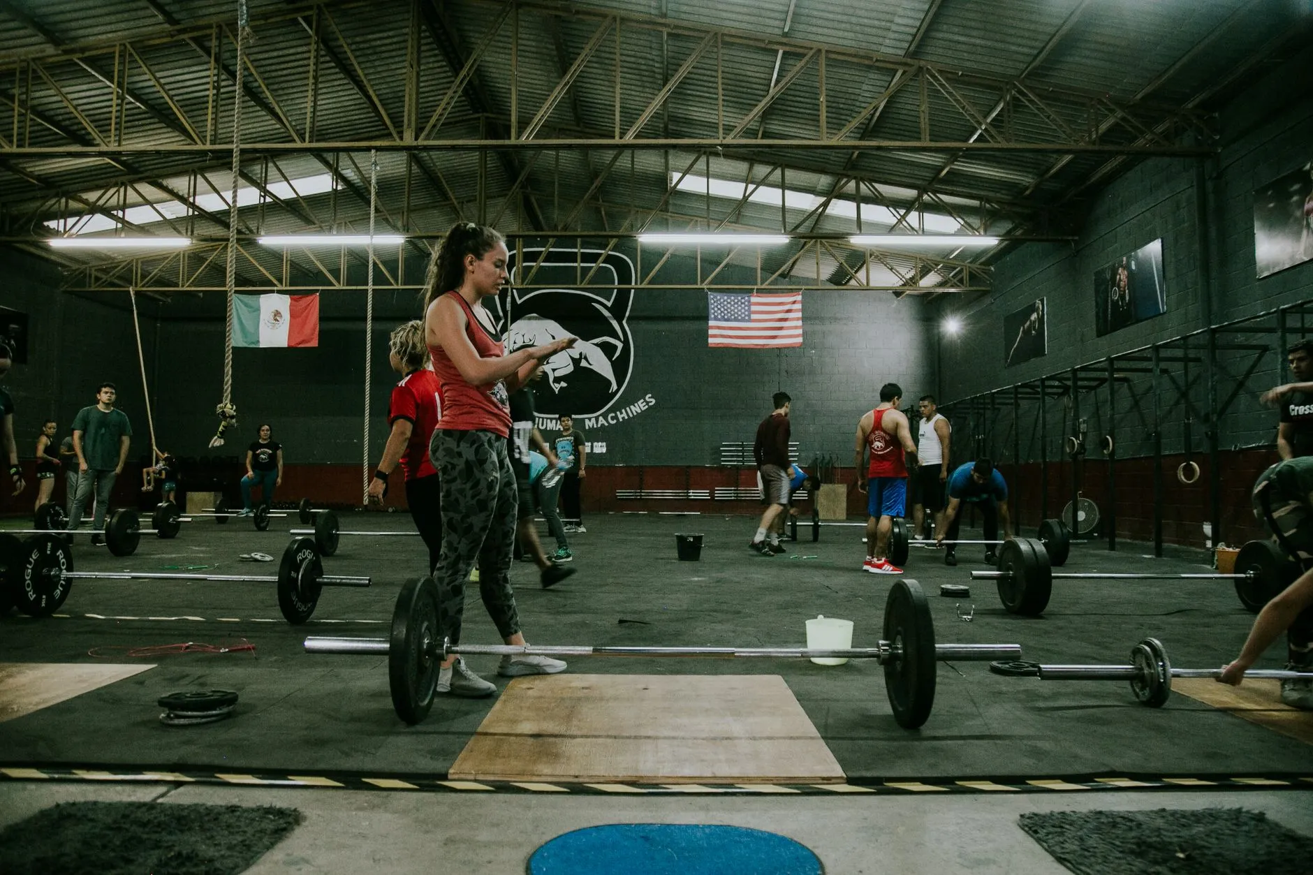athletes training hard with barbells in a dark industrial crossfit gym