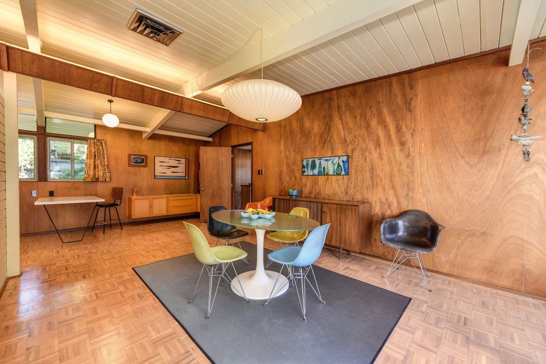 a mid-century modern dining area with a tulip table and eames-style chairs
