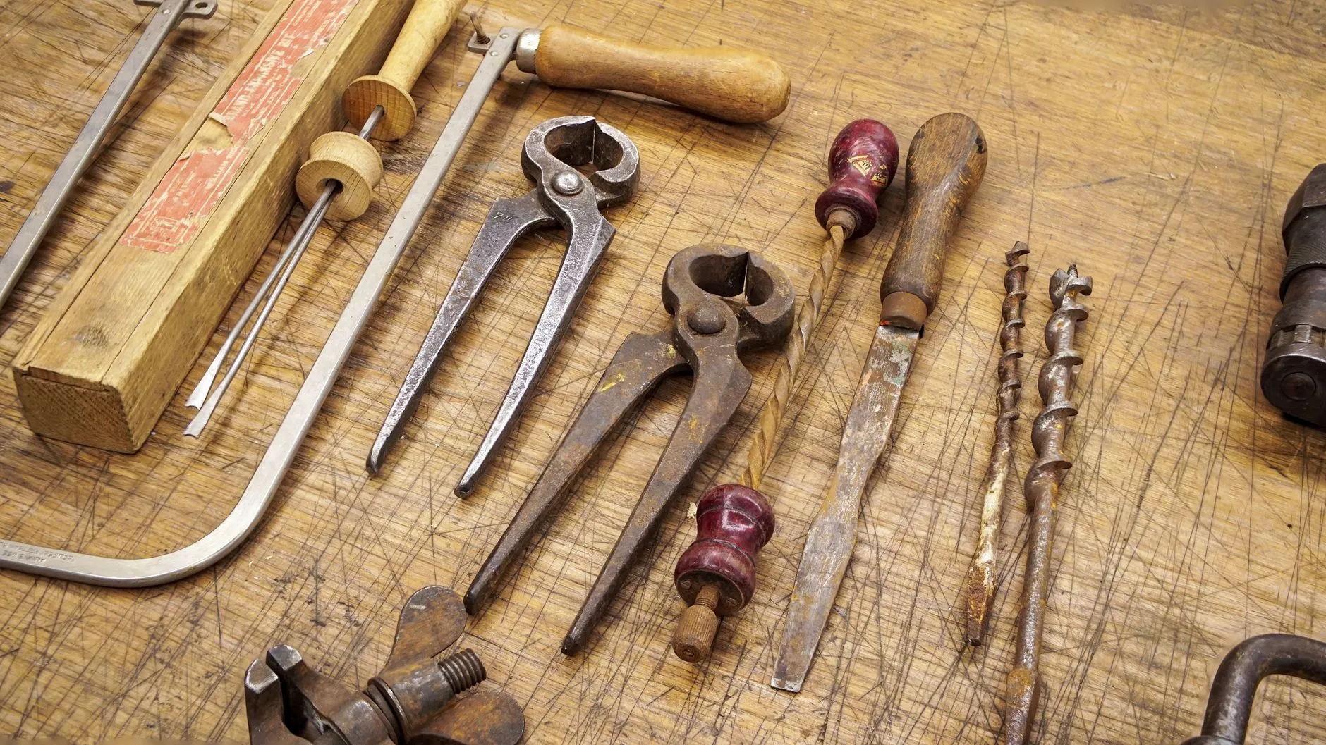 antique hand tools laid out on a worn bench
