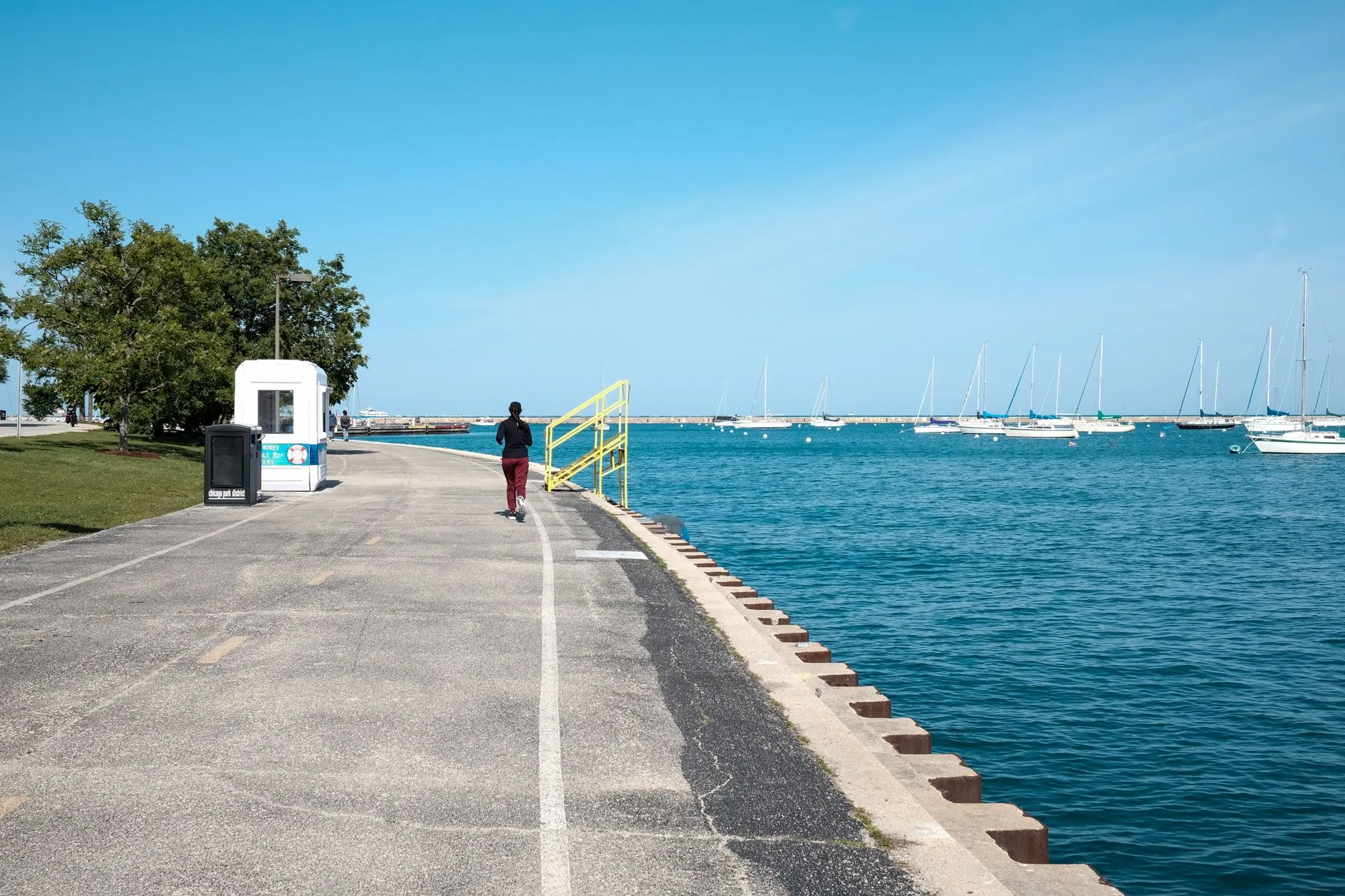 a lakefront path beside blue water on a sunny day