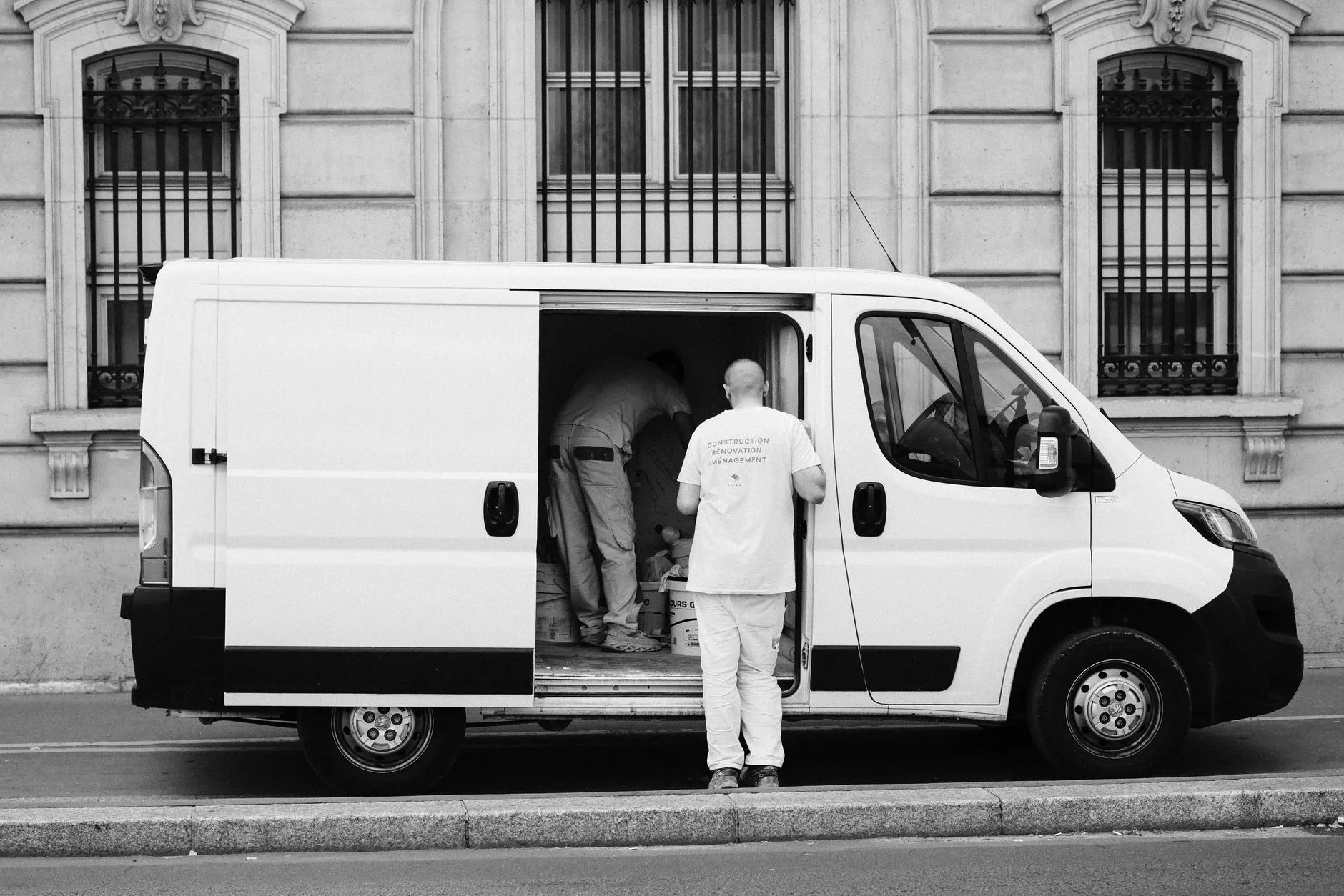 technician in plain workwear loading equipment into an unmarked white van