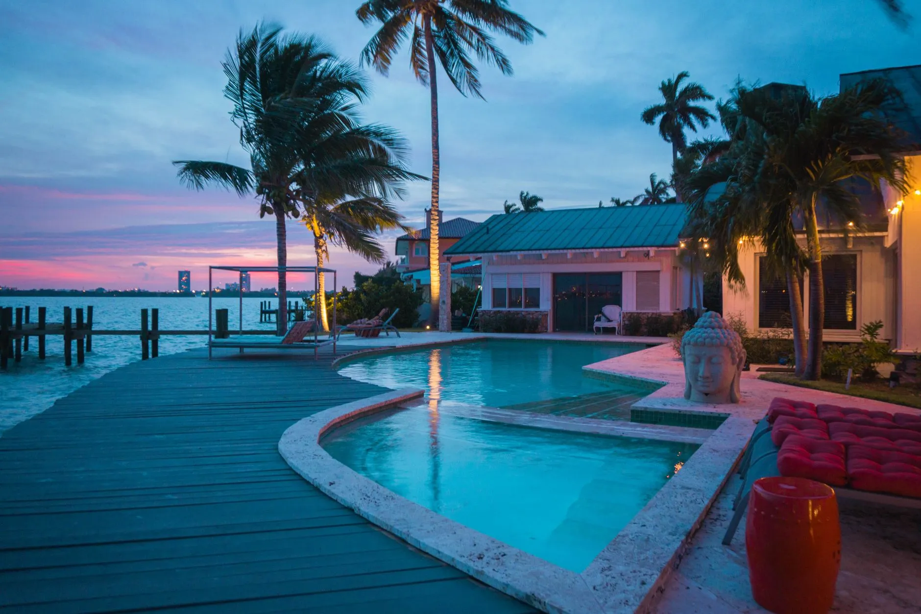 curved pool on a bayfront deck with palm trees at dusk