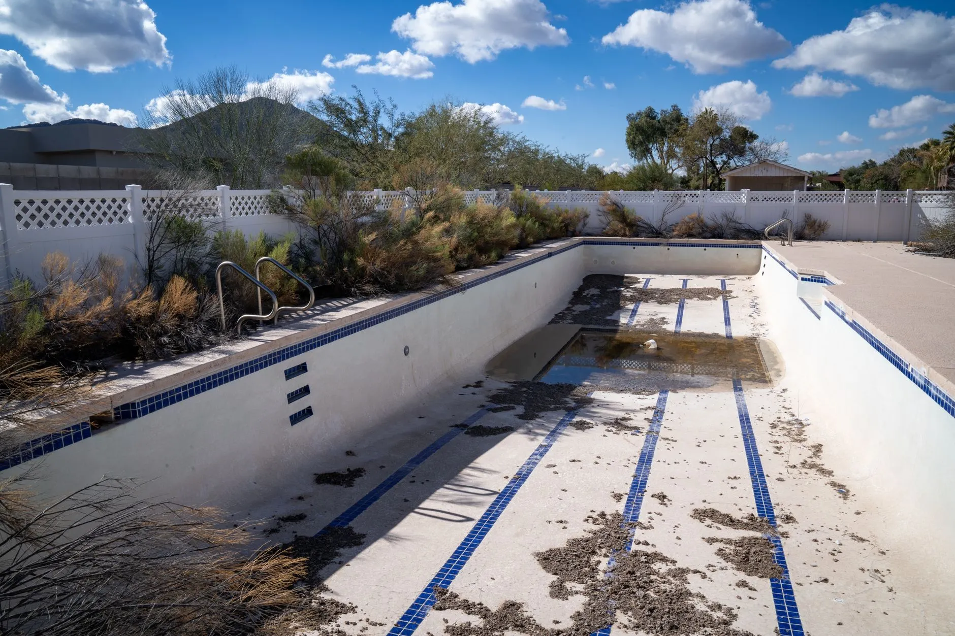 drained backyard pool with debris on the floor