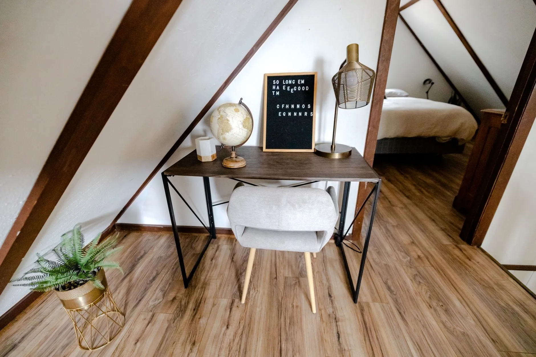 Attic office with a desk and chair beneath exposed beams