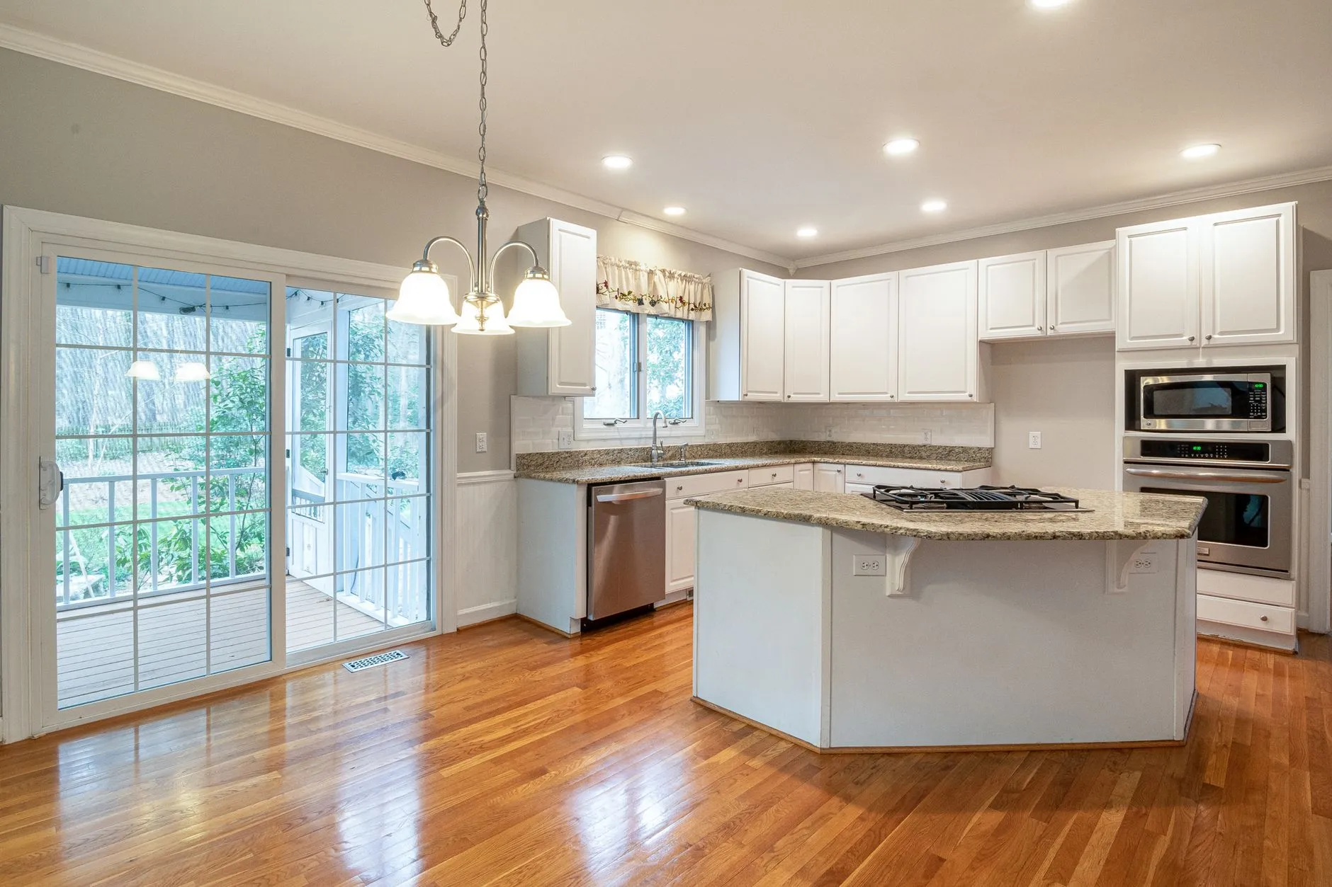 a bright kitchen with white cabinet doors, an island and wood flooring