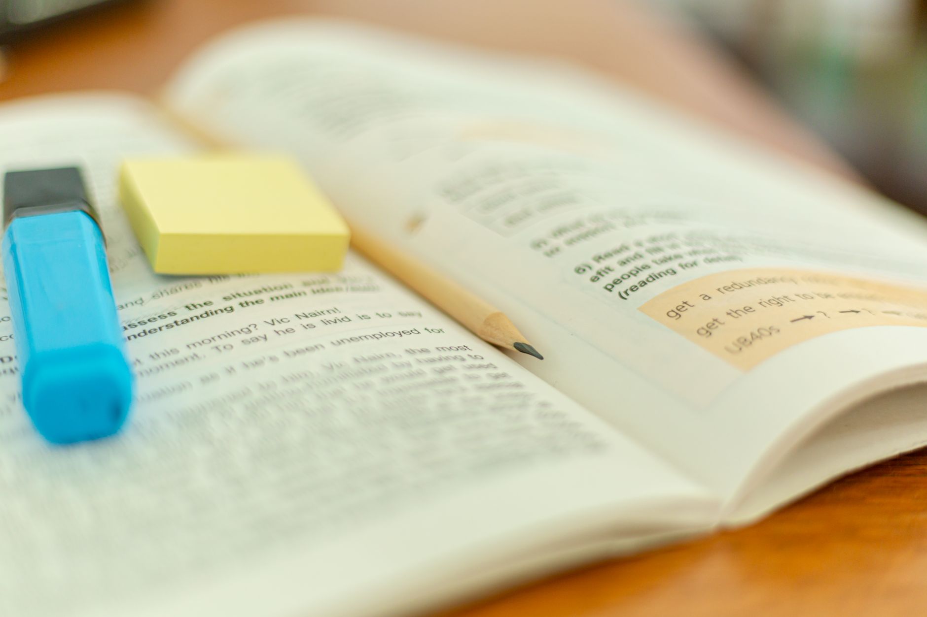 an open book with a sticky note and a highlighter
