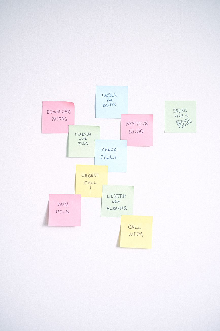 colorful sticky notes with handwritten tasks arranged on a white wall