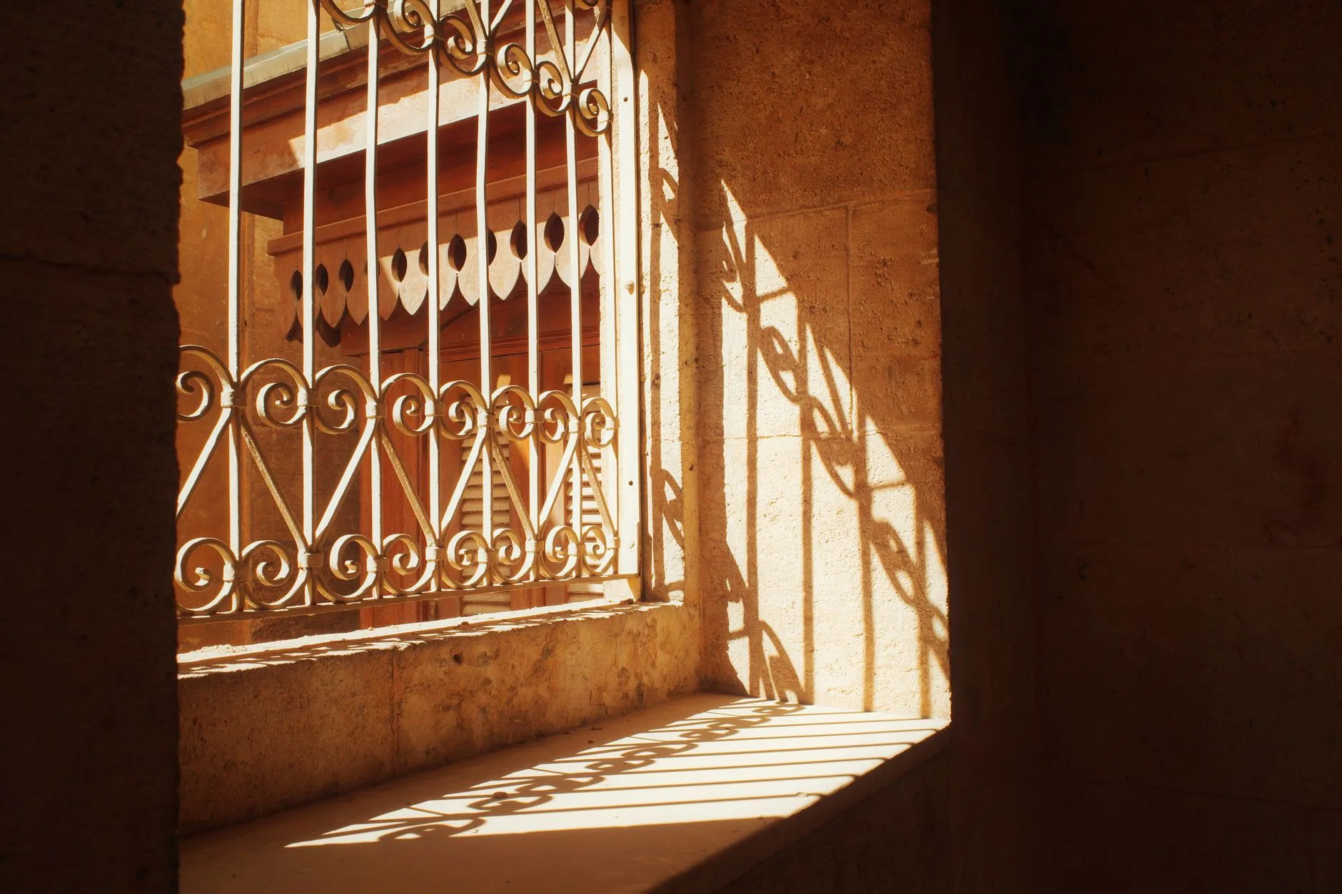 sunlight through an ornate metal grille casting patterned shadows