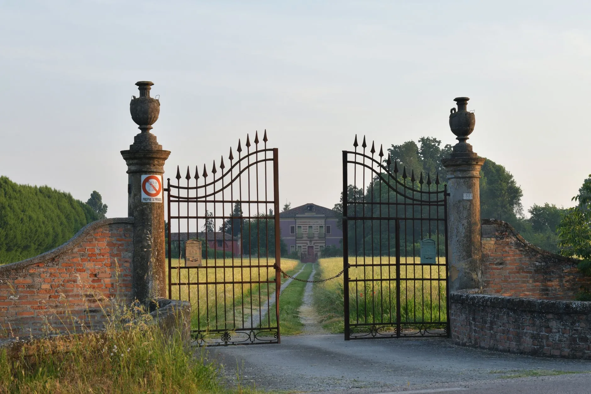 iron driveway gates before a golden field at dusk