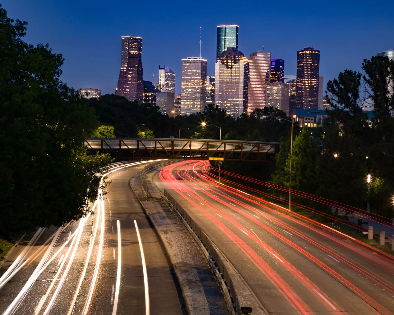 highway light trails leading into the Houston skyline at dusk