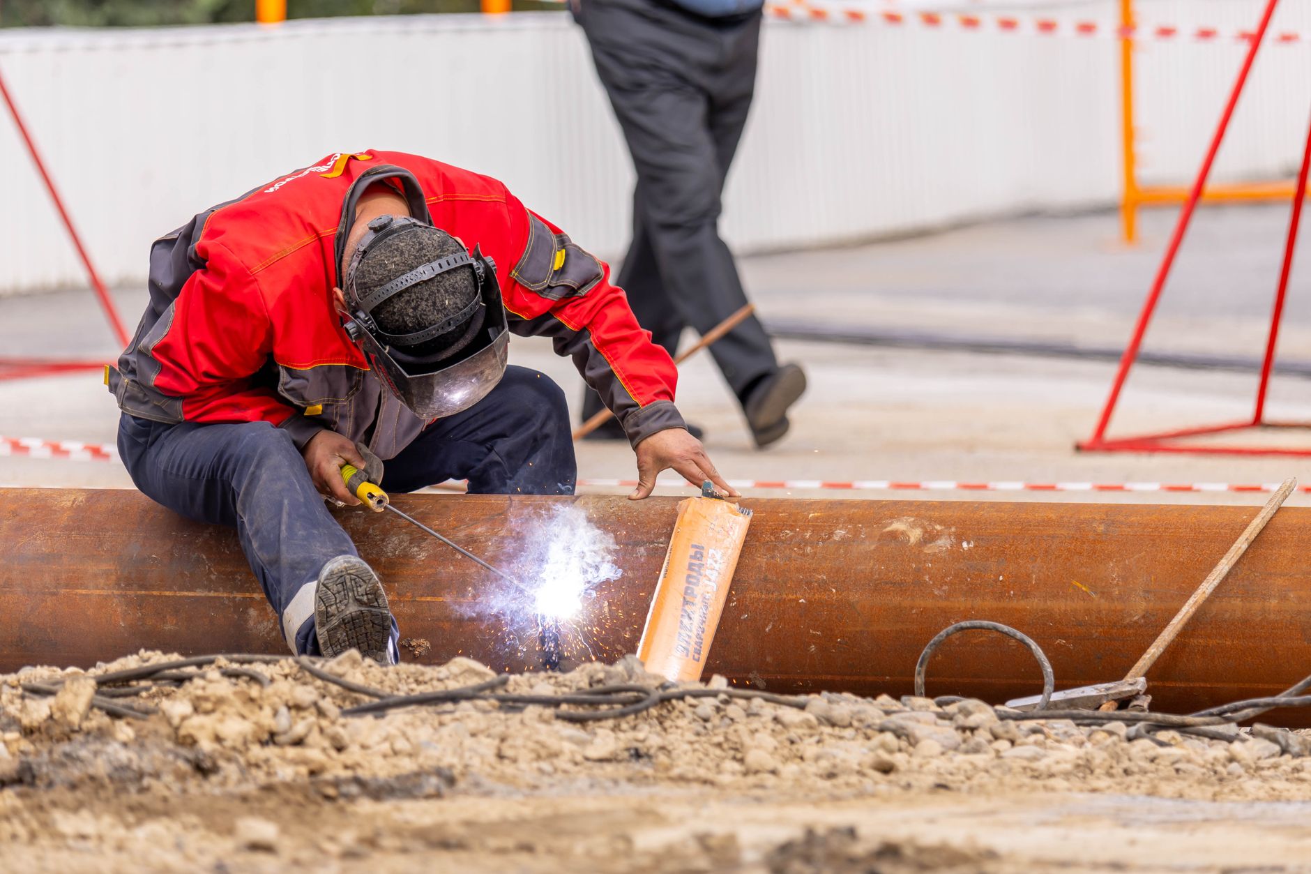 a rig welder joining a pipe section at a dirt job site