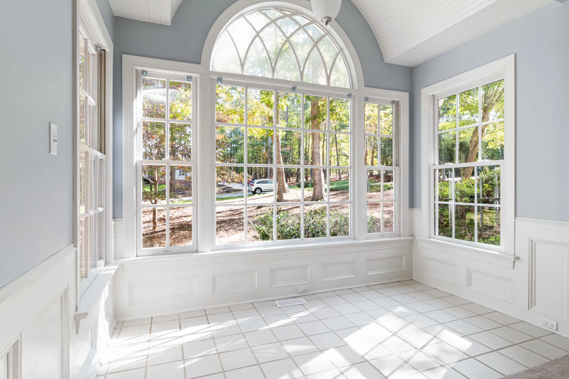 bright sunroom with an arched window and walls of glass