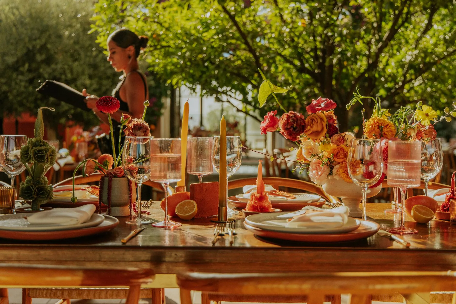 wedding coordinator arranging place settings at an elegant outdoor reception