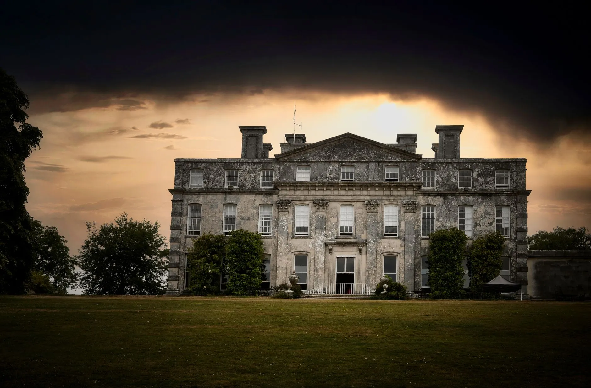 a historic mansion facade with wedding guests arriving at dusk