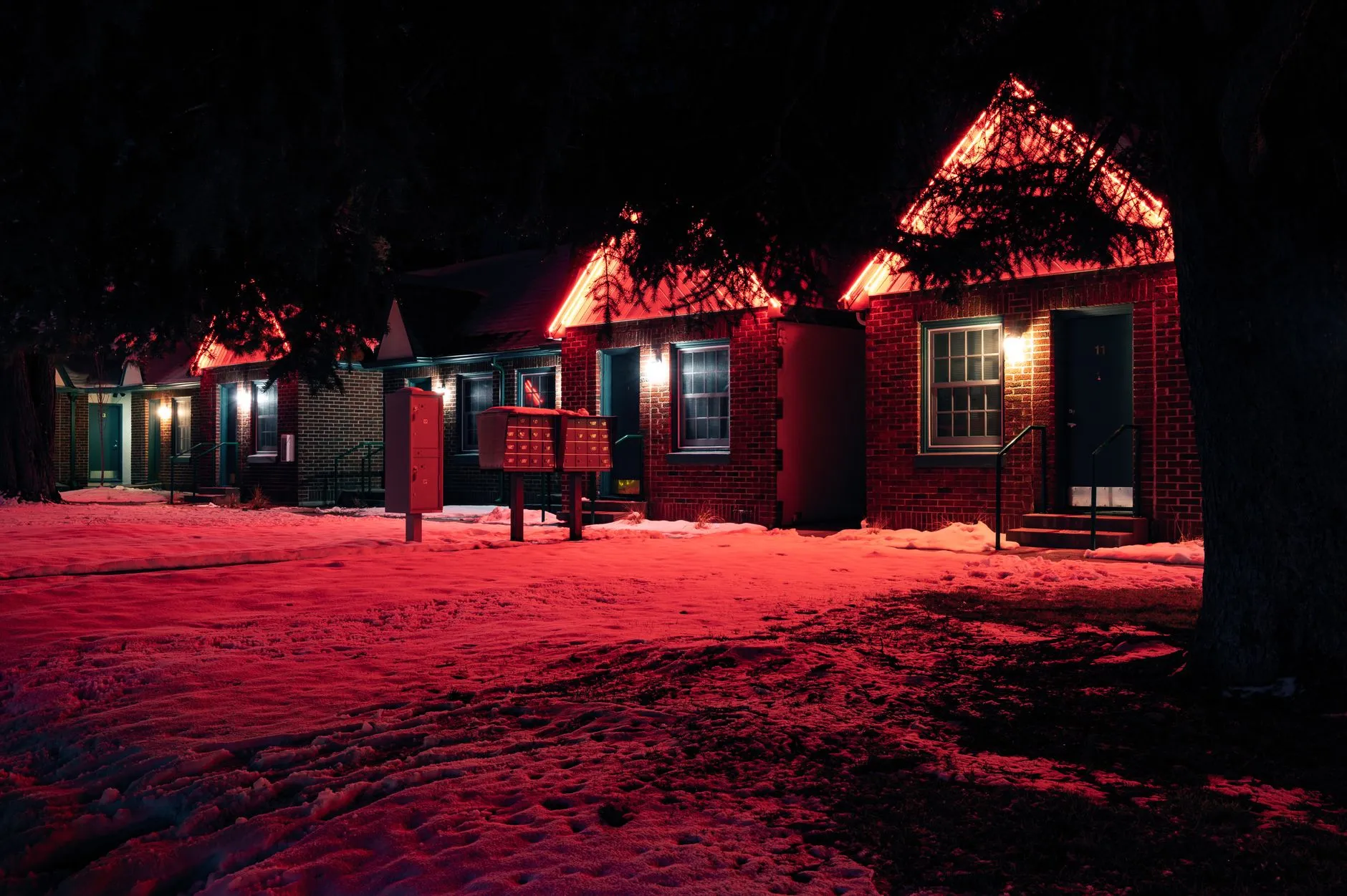 row of brick houses with red lights along the rooflines at night