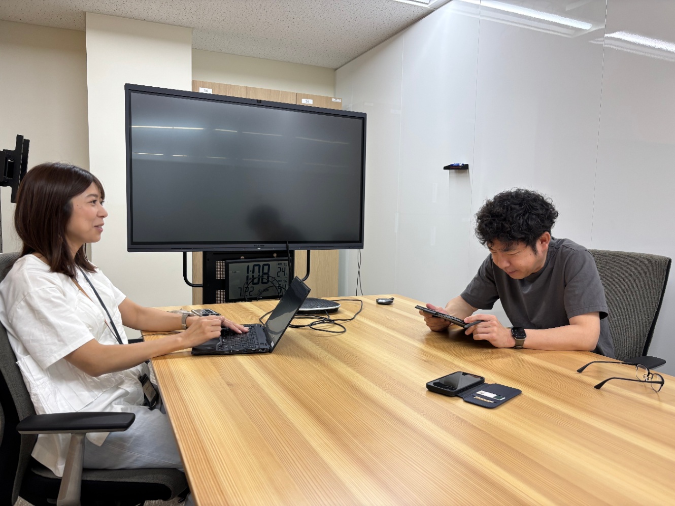 オフィス内の会議室にて向かい合って話している2人