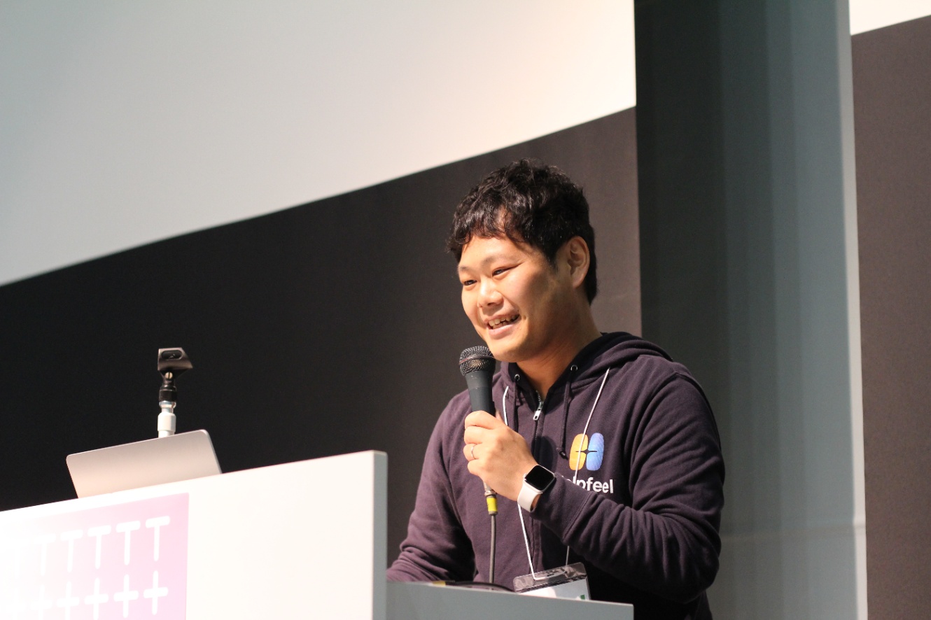 sussanが登壇発表する様子。Helpfeelのパーカーを着て、マイクを持ち、発表している。